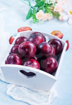 fresh plums in box and on a table
