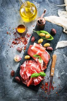 prosciutto with olives and spice on a table