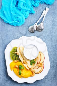 Vegan dietary food. Vitamins Summer dessert. Salad of fresh organic fruits mango banana kiwi nuts fresh mint