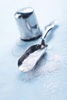 sea salt in metal spoon and on a table