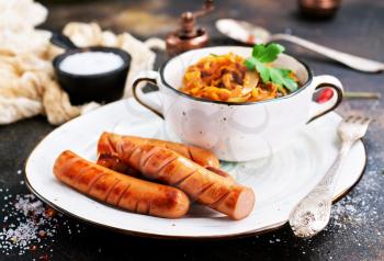 sausages with fried cabbage in bowl and on a table