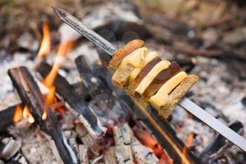 Cheese and bread roasted on fire on metal sticks