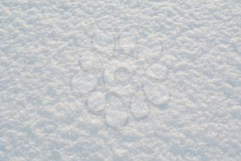 Snow surface with shiny snowflakes under bright winter sunlight close-up view, winter abstract natural background