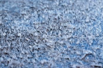 White hoarfrost crystals on flat surface close-up view with selective focus, shallow depth of field.