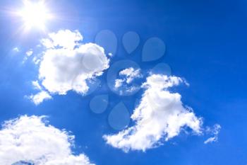 Bright sun and clouds on a blue sky background