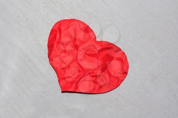 Abandoned crumpled red paper heart on a dirty shaded background