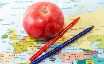 Red apple and pens on the map of Europe