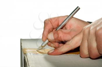 Hands with a knife-scalpel open a carton box isolated on a white background