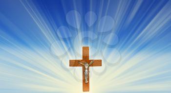 Wooden cross crucifix in the rays of light on a blue background