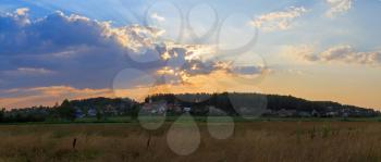 Panoramic photo. Sunset in the countryside. Bright sky with beautiful clouds.