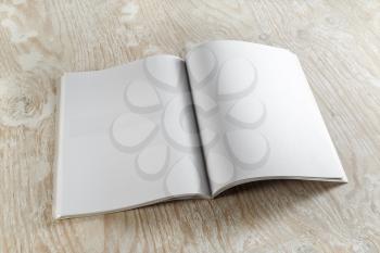 Blank opened magazine on light wooden background with soft shadows. For design presentations and portfolios.
