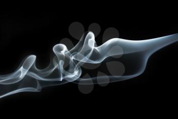 Photo of abstract smoke swirls and waves on black background. Studio shot.