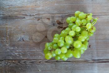 Bunch of ripe tasty sweet green grapes on old wooden background. Top view.