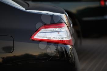 Closeup of a taillight on a modern black car with reflection. Shallow depth of field. Selective focus.