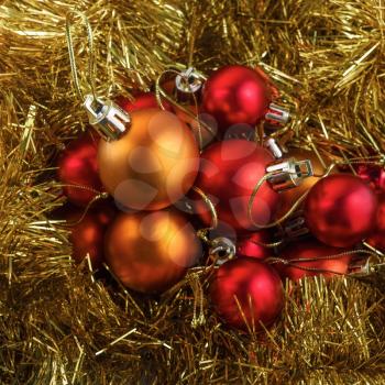 Set of red and orange Christmas balls on a background of golden shiny tinsel.