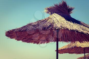 Straw beach umbrella on a background of the cloudless sky.