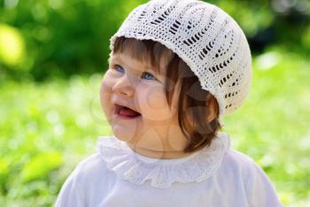 Laughing baby in a white knitted cap outdoor. Shallow depth of field. Selective focus.