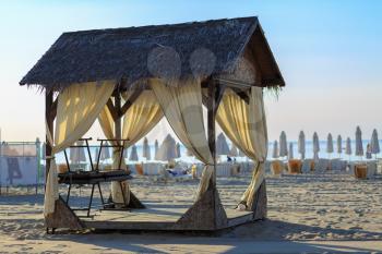 Massage canopy with thatched roof on the sandy beach. Early morning. Shallow depth of field. Selective focus.