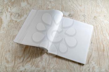 Blank opened magazine on light wooden background with soft shadows. For design presentations and portfolios.