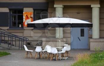 Summer cafe in the city. Tables, chairs and umbrella. Blank template for graphic designers. Shallow depth of field. Selective focus.