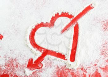 Heart with arrow drawn in the white flour.