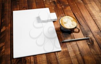 Photo of blank stationery set. Corporate identity template on vintage wooden table background. Letterhead, business cards, coffee cup and pen.