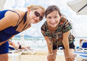 Cute funny young women making selfie. Two sisters are photographed on a beach background. Selective focus.