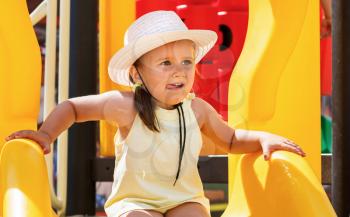 A child in a white hat and a yellow t-shirt on the playground on a sunny day. Shallow depth of field. Focus on the model's face.