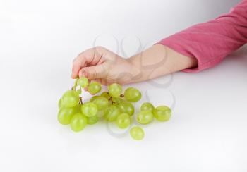 Children's hand takes a bunch of tasty green grapes.
