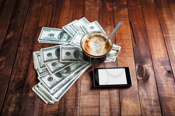 Coffee cup, money, dollars and phone on vintage wooden table background. Business concept.