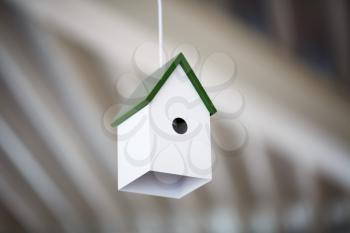 Chandelier birdhouse. Lamp in the form of a white birdhouse with a green roof. Shallow depth of field. Selective focus.