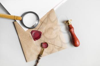 Envelope, magnifier, seal, stamp, spoon on paper background. Responsive design mockup. Vintage still life with postal accessories. Blank stationery. Top view.