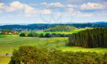 Summer rural landscape. Green fields, trees and blue sky with clouds. Minsk region, Belarus.