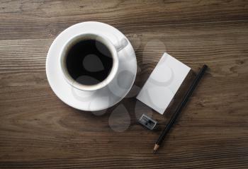 Coffee and stationery. Coffee cup, saucer, bank business cards, pencil and sharpener on wood table background. Flat lay.