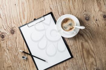 Photo of clipboard with blank letterhead, coffee cup, pencil and sharpener on wooden background. Blank stationery template. Top view.