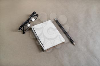 Photo of blank notebook, pencil and glasses on craft paper background.