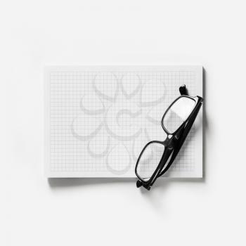 Blank copybook and glasses on white paper background. Top view. Flat lay.