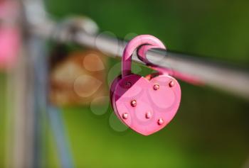 Closed pink heart shaped padlock. Symbol of eternal love. Tradition of lovers on the wedding day. Selective focus.