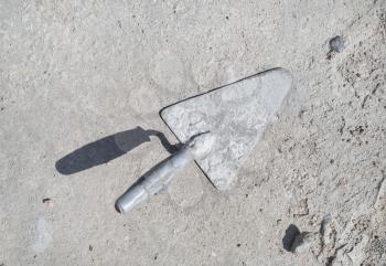 Old masonry trowel on gray concrete background. Flat lay.
