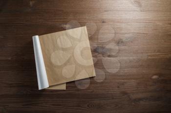 Blank notepad of kraft paper on wooden background. Mockup for your design. Flat lay.
