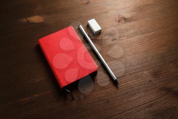 Red notebook, pencil and eraser on wooden background. Template for branding identity.