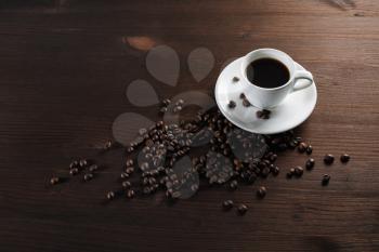 Coffee cup and coffee beans on wooden kitchen table background. Copy space for your text.