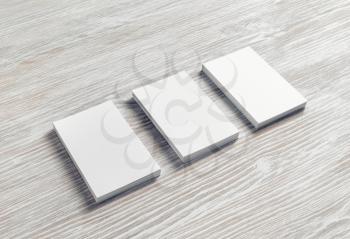 Three blank business cards on light wooden background. Branding mockup.