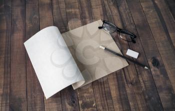 Blank brochure, glasses, pencil and eraser, on wooden table background. Responsive design mockup.