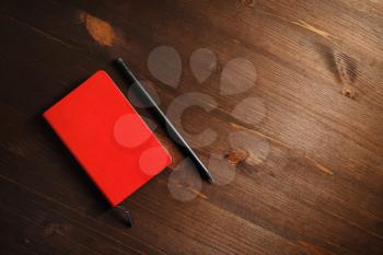 Blank red notebook and pencil on wood table background. Template for branding identity. Flat lay.