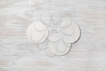 Photo of blank beer coasters on light wooden background. Template for placing your design. Top view. Flat lay.