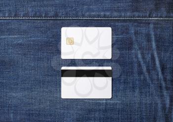 Two white plastic chip cards on denim background. Credit cards. Front and back view. Flat lay.