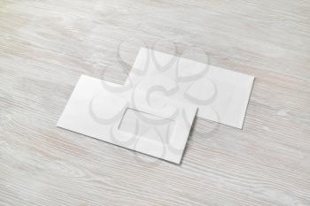 Photo of two blank paper envelopes on light wooden background. Back and front.