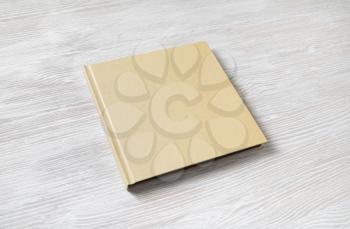 Blank square cover book on light wooden background.