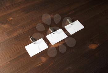 Three blank white badges on wood table backgroun. Space for text.
